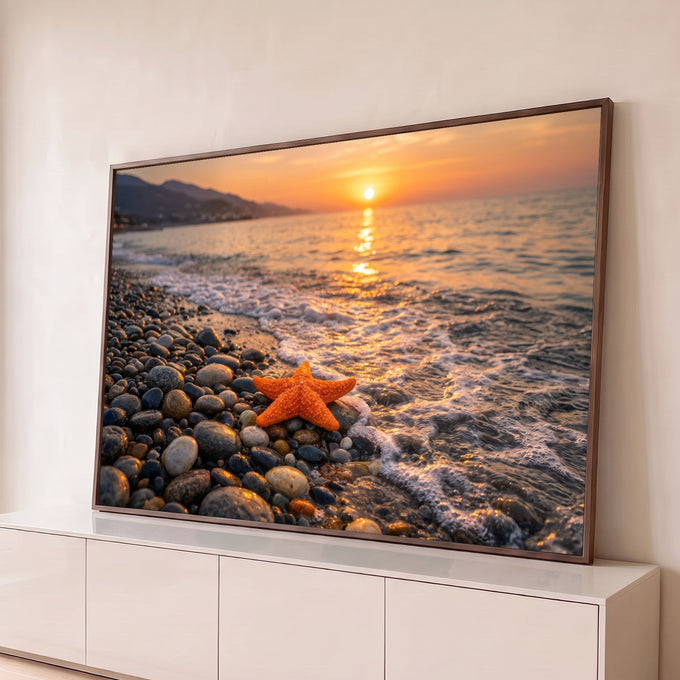 Estrela-do-mar laranja sobre seixos na beira do mar com ondas e pôr do sol dourado ao fundo, quadro decorativo