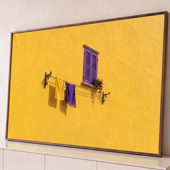 Parede amarela com janela de venezianas roxas, flores e varal com toalhas amarela e roxa, quadro decorativo