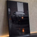 Muscle car preto molhado de chuva com farol laranja aceso refletido no asfalto, quadro decorativo