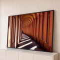 Corredor de arcos em Bolonha, tons terracota, sombras diagonais e pessoa caminhando, quadro decorativo