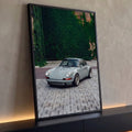 Porsche 911 clássico cinza estacionado em piso de pedras diante de parede coberta de hera, quadro decorativo