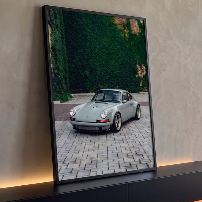 Porsche 911 clássico cinza estacionado em piso de pedras diante de parede coberta de hera, quadro decorativo