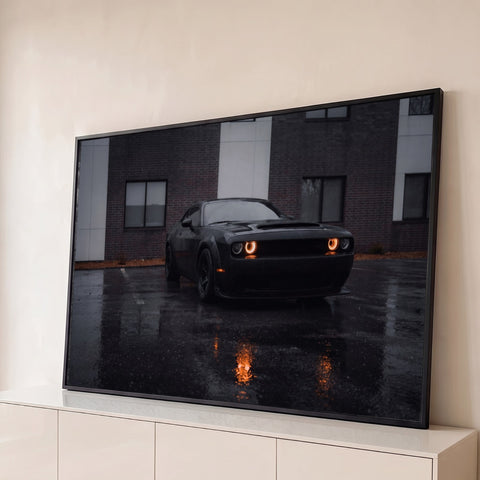 Carro esportivo preto com faróis laranja acesos em estacionamento molhado pela chuva, quadro decorativo