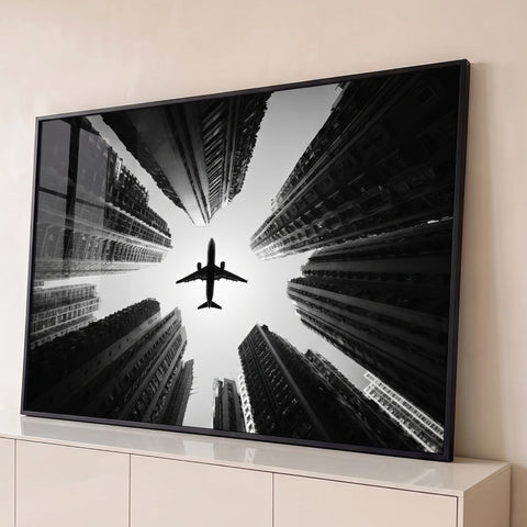 Fotografia preto e branco de avião voando entre arranha-céus vistos de baixo, quadro decorativo