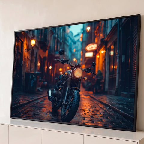 Motocicleta preta com farol aceso em rua de pedras molhada à noite, luzes âmbar, quadro decorativo