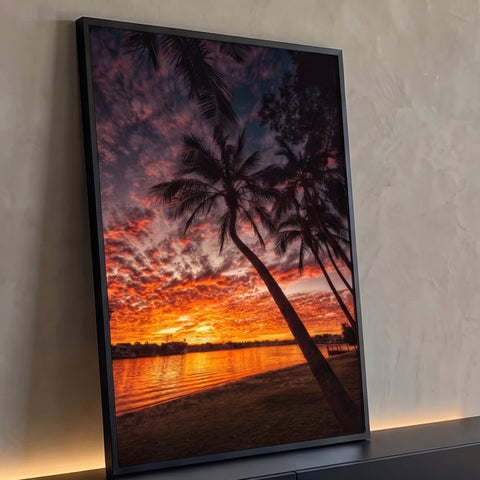 Palmeiras em silhueta diante de céu laranja e vermelho do pôr do sol refletido no lago, quadro decorativo