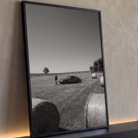 Porsche clássico e mulher em campo com fardos de feno em fotografia preto e branco, quadro decorativo