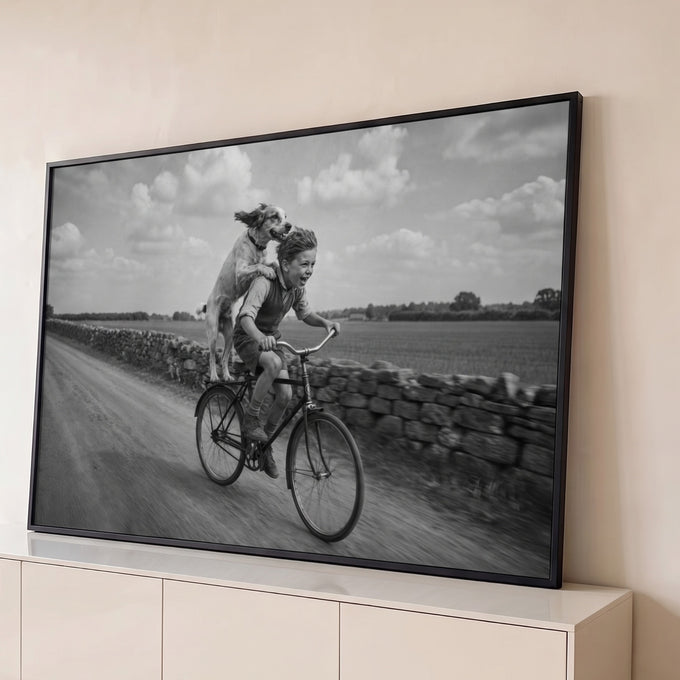 Quadro Decorativo Grande Menino e Cão para Sala Preto | quadros decorativos para sala | menino sorridente pedalando bicicleta com cão em pé no bagageiro, foto preto e branco | Porao dos Quadros