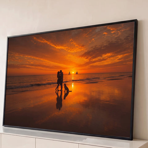 Silhueta de casal se beijando com cachorro na praia ao pôr do sol laranja e veleiros, quadro decorativo