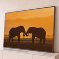 Silhueta de dois elefantes com as trombas unidas na savana ao pôr do sol laranja, quadro decorativo