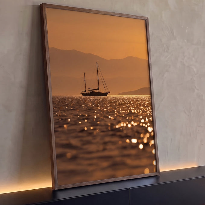 Veleiro em silhueta sobre mar cintilante ao pôr do sol laranja com montanhas, quadro decorativo