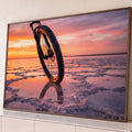 Quadro Decorativo Grande Bicicleta no Pôr do Sol para Sala | quadros decorativos para sala | roda de bicicleta em destaque sobre salar refletindo pôr do sol colorido | Porao dos Quadros