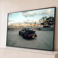 Quadro Decorativo Grande Carro Esportivo Skyline para Sala | quadros decorativos para sala | carro esportivo preto visto de trás em estacionamento com skyline urbano ao fundo | Porao dos Quadros
