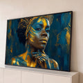 Mulher negra com pintura corporal dourada, toucado de ouro e mão no queixo em fundo azul, quadro decorativo
