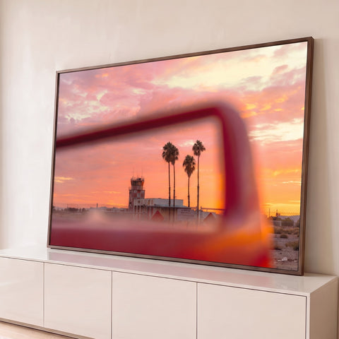 Pôr do sol rosa e laranja com palmeiras e torre de controle vista por moldura vermelha, quadro decorativo