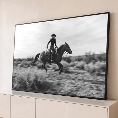 Cowgirl de chapéu cavalgando a galope no deserto, fotografia em preto e branco, quadro decorativo