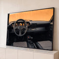 Interior de Porsche 911 clássico com volante preto, painel laranja e bancos pied-de-poule, quadro decorativo