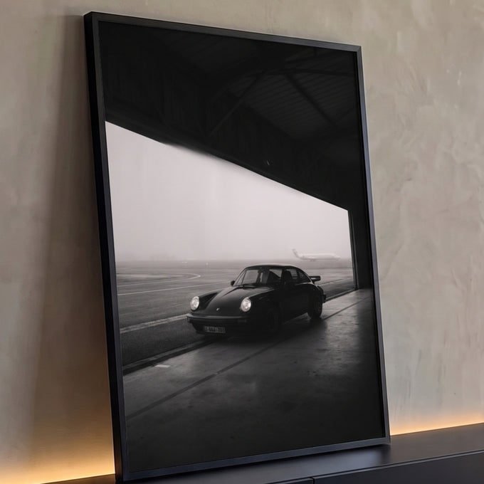 Porsche 911 clássico preto em hangar com avião na neblina, fotografia preto e branco, quadro decorativo