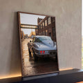 Corvette 63 prata visto de trás em rua de tijolos e prédios industriais ao pôr do sol, quadro decorativo