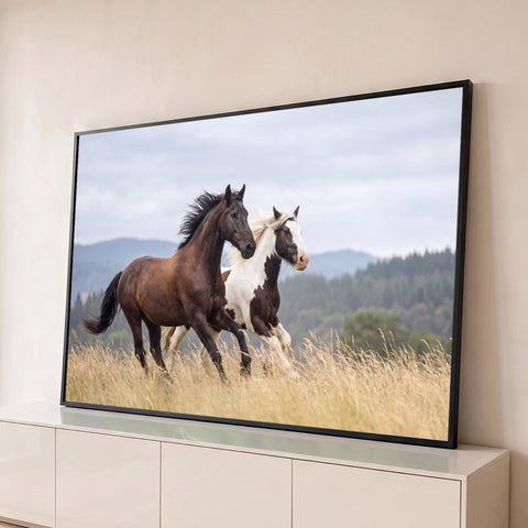 Cavalo castanho e cavalo pampa galopando em campo de grama dourada com montanhas, quadro decorativo