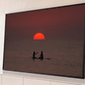 Quadro Decorativo Grande Casal Surfistas para Sala Vermelho | quadros decorativos para sala | silhuetas de duas pessoas em prancha de surfe diante de pôr do sol vermelho intenso | Porao dos Quadros