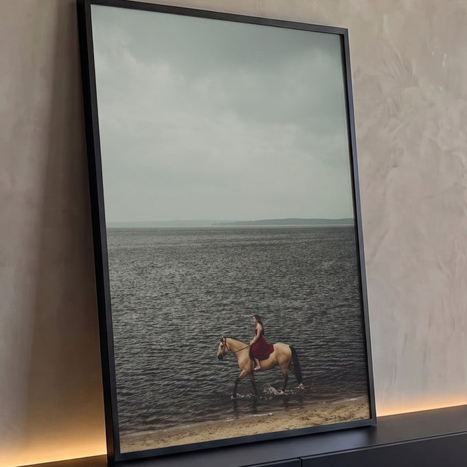 Mulher de vestido vermelho montada em cavalo baio na beira do mar sob céu nublado, quadro decorativo