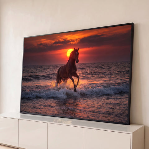 Cavalo alazão galopando nas ondas do mar com sol se pondo ao fundo em céu vermelho, quadro decorativo