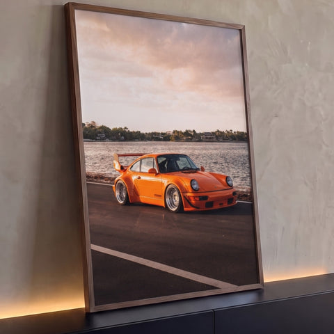 Quadro Decorativo Grande Carro Pôr do Sol para Sala Laranja | quadros decorativos para sala | carro esportivo laranja com aerofólio traseiro junto à água no pôr do sol | Porao dos Quadros