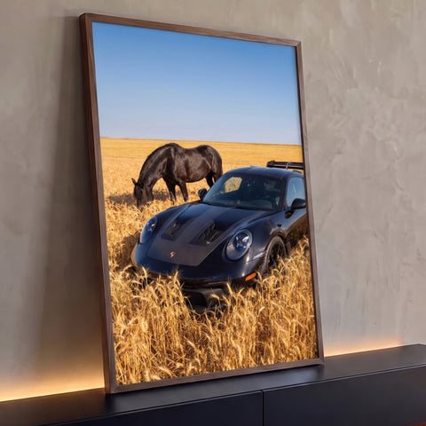 Porsche preto em campo de trigo dourado, cavalo preto pastando e céu azul, quadro decorativo