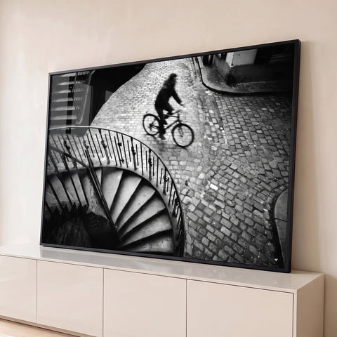 Ciclista em rua de paralelepípedos e escada espiral de ferro, fotografia preto e branco, quadro decorativo