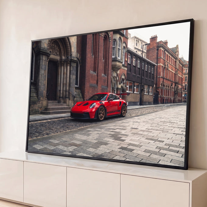 Porsche 911 GT3 RS vermelho com rodas bronze em rua de paralelepípedos e prédios antigos, quadro decorativo