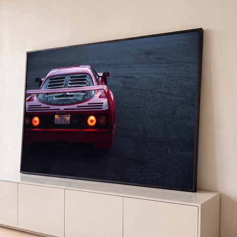 Ferrari F40 vermelha vista de trás com lanternas acesas sobre asfalto escuro ao anoitecer, quadro decorativo