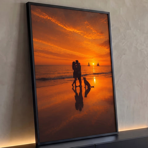 Silhueta de casal se beijando na praia com cachorro, veleiros e céu laranja ao pôr do sol, quadro decorativo