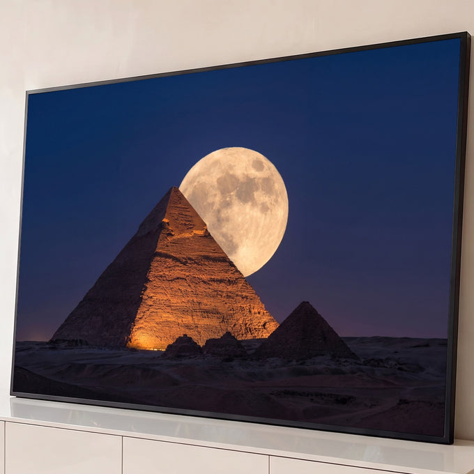 Quadro Decorativo Grande Pirâmide de Gizé para Sala Laranja | quadros decorativos para sala | pirâmide egípcia iluminada em laranja com lua cheia atrás do topo contra céu azul escuro | Porao dos Quadros