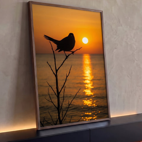Pássaro em silhueta num galho seco diante do sol se pondo no mar laranja, quadro decorativo