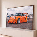Porsche 911 laranja widebody com rodas raiadas e aerofólio em marina com barcos, quadro decorativo