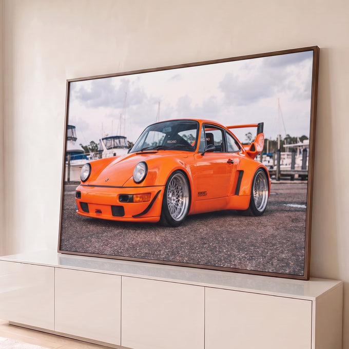 Porsche 911 laranja widebody com rodas raiadas e aerofólio em marina com barcos, quadro decorativo