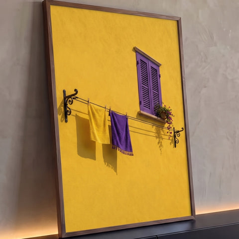 Parede amarela com janela roxa, vaso de flores e varal com toalhas amarela e roxa, quadro decorativo