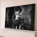 Fotografia preto e branco de menino de cabelos cacheados abraçando um cordeiro branco, quadro decorativo