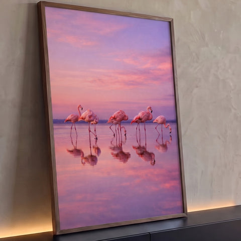 Flamingos rosa caminhando em lagoa espelhada sob céu lilás ao pôr do sol, quadro decorativo