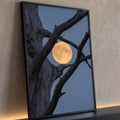 Lua cheia dourada entre galhos de tronco seco retorcido contra céu azul do crepúsculo, quadro decorativo