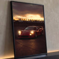 Ferrari F40 vermelha com faróis acesos em asfalto sob céu de pôr do sol alaranjado, quadro decorativo