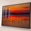 Quadro Decorativo Grande Flamingos Alçando para Sala Laranja | quadros decorativos para sala | flamingos em silhueta alçando voo sobre lago durante pôr do sol vermelho e laranja | Porao dos Quadros