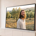 Jesus sorrindo de túnica bege em olival ao pôr do sol, luz dourada e colinas ao fundo, quadro decorativo
