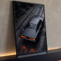 Muscle car preto fosco visto de cima em rua molhada com lanternas laranja acesas, quadro decorativo