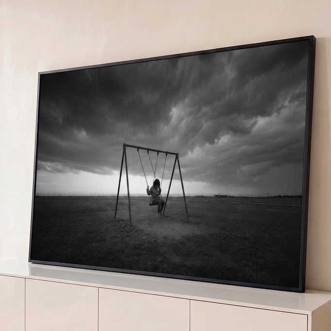 Menina sozinha num balanço em campo aberto sob nuvens de tempestade, foto preto e branco, quadro decorativo