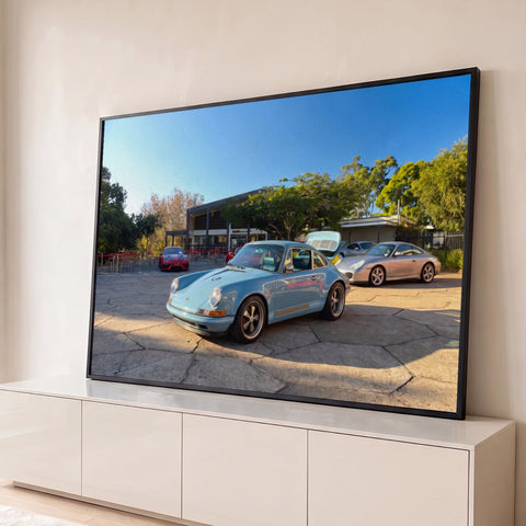 Porsche 911 clássico azul-claro em pátio de pedra com esportivos e árvores, efeito óleo, quadro decorativo
