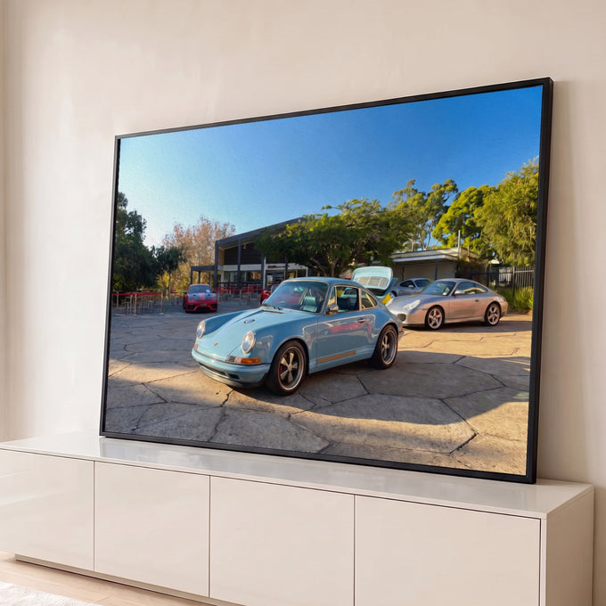 Porsche 911 clássico azul-claro em pátio de pedra com esportivos e árvores, efeito óleo, quadro decorativo