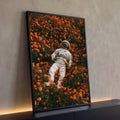 Quadro Decorativo Astronauta Deitado em Campo de Flores | quadros decorativos para sala | astronauta de traje branco deitado em campo de flores laranja vibrantes | Porao dos Quadros
