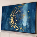 Cardume de peixes dourados em espiral sobre fundo azul texturizado com feixe de luz, quadro decorativo
